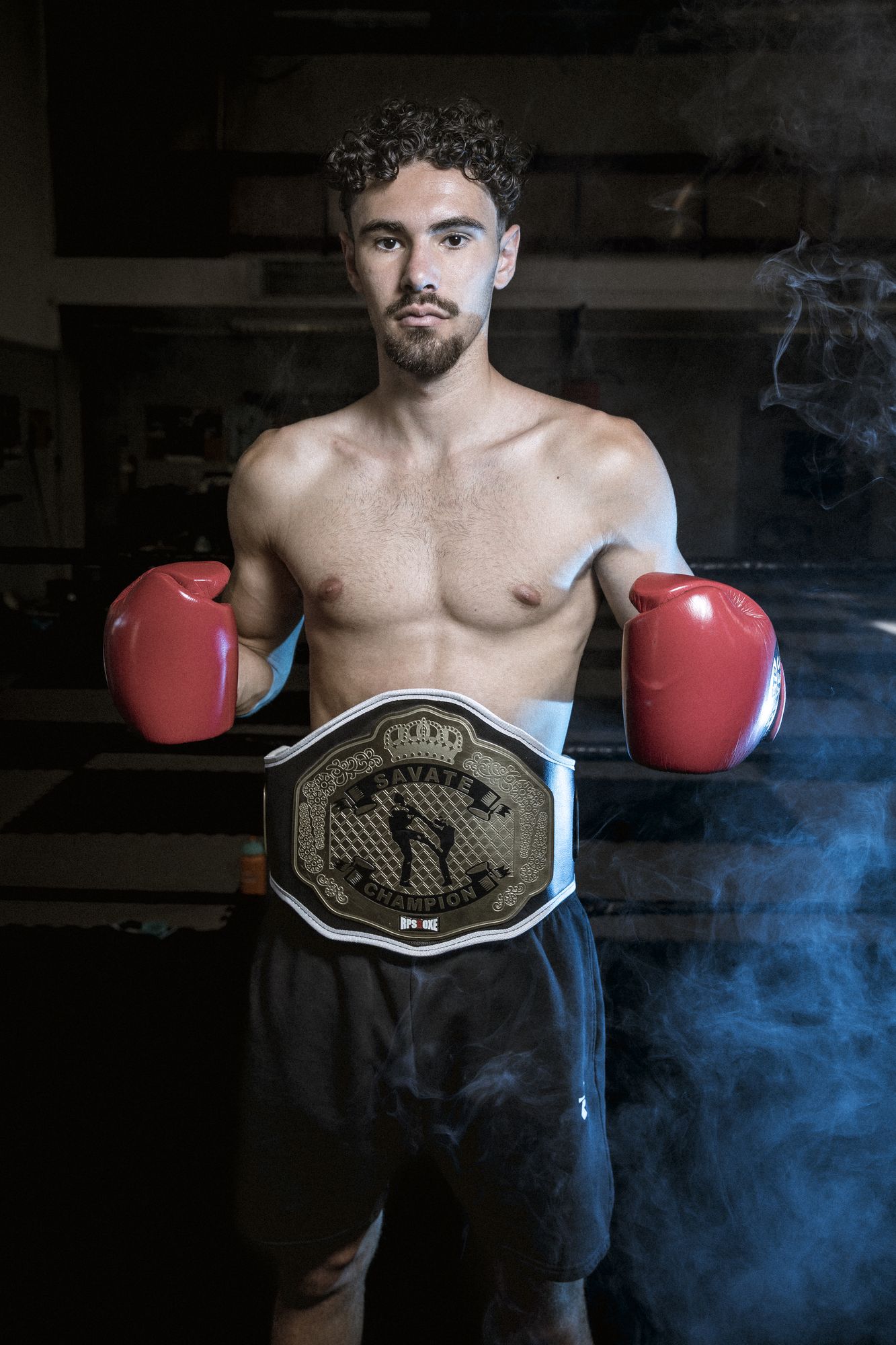 Portrait d'un champion de savate avec sa ceinture, fumée bleue